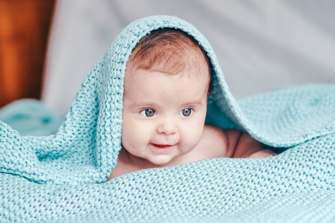 Cute baby hiding under a blue blanket