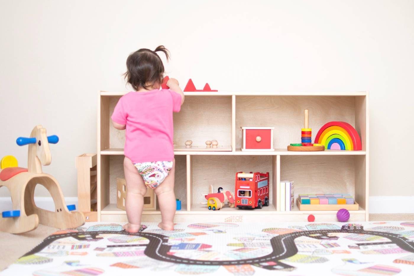 A toddler browses toys in a low shelf