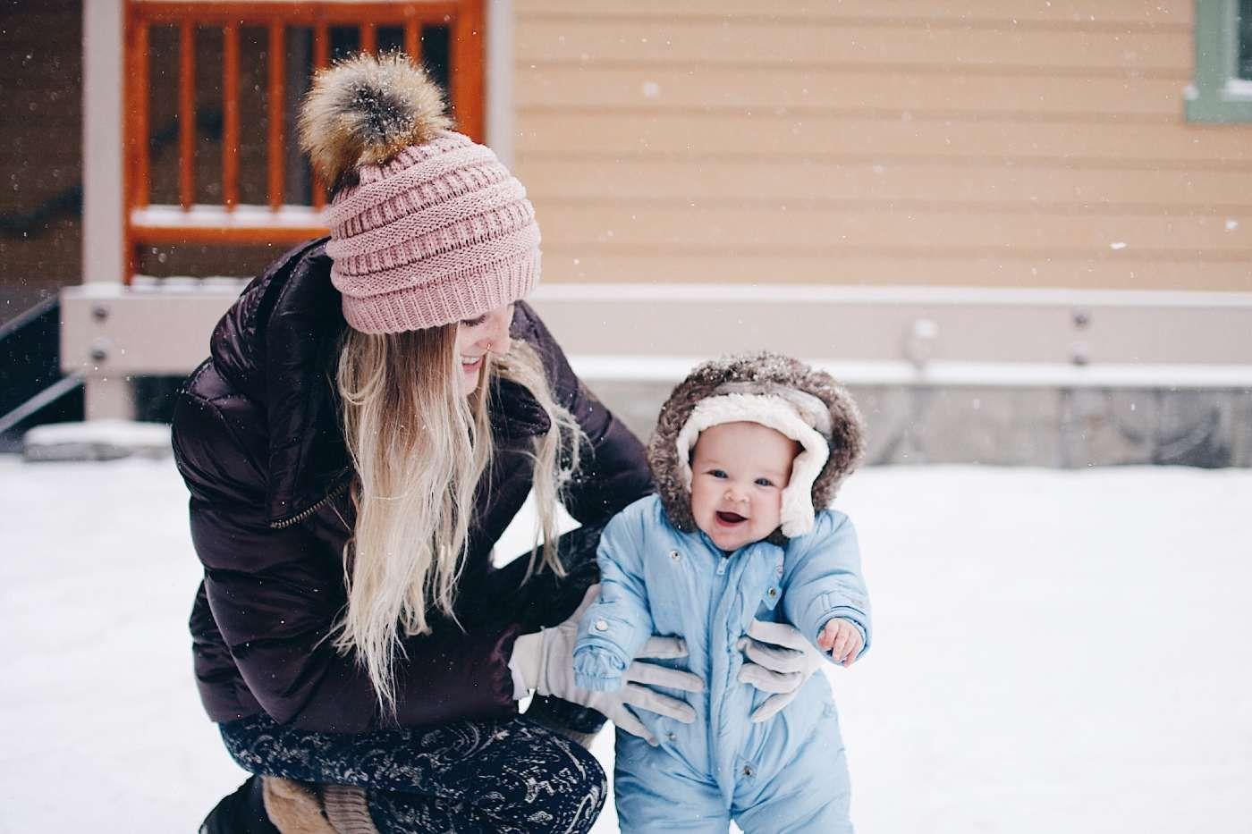 Cold weather tips for babies and toddlers - bundled up baby playing in snow with momr
