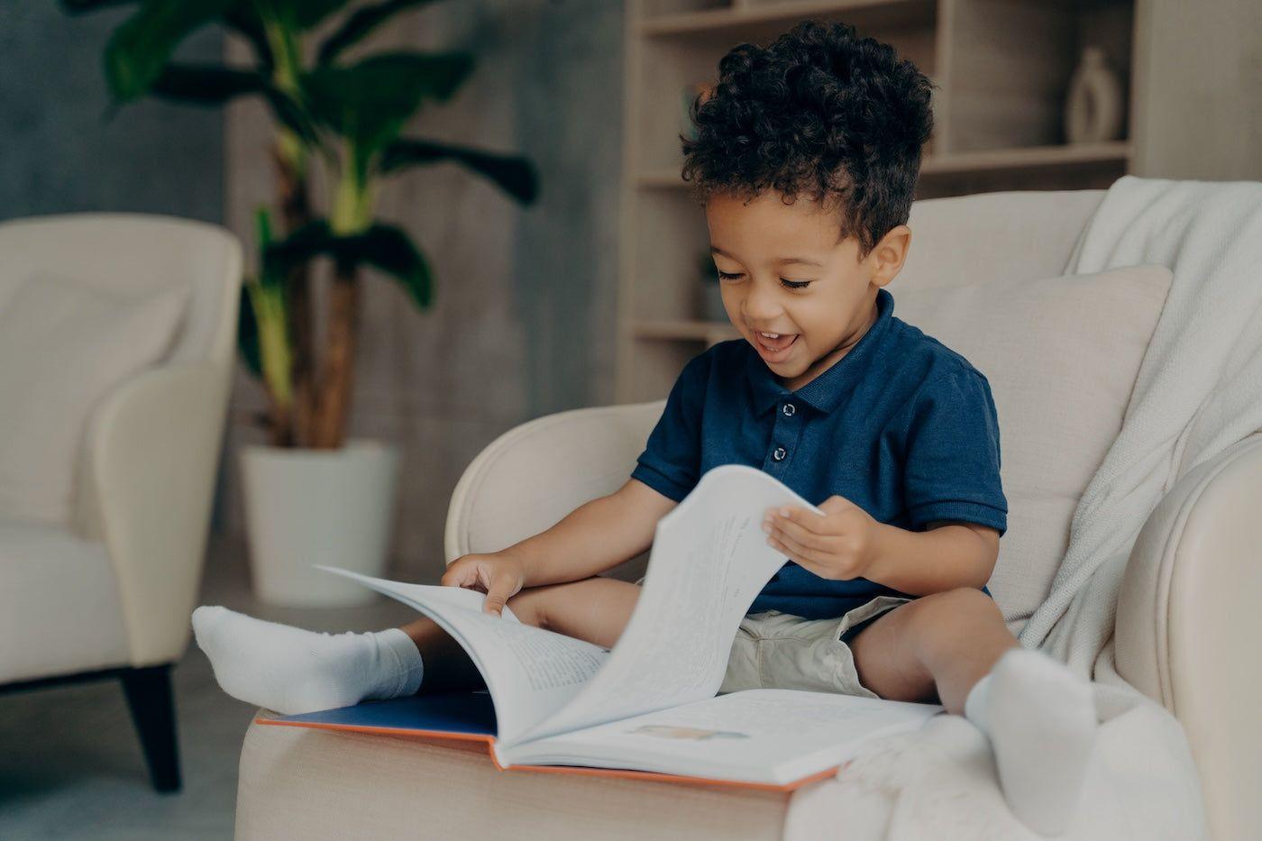 A 3-year-old boy happily reads a book