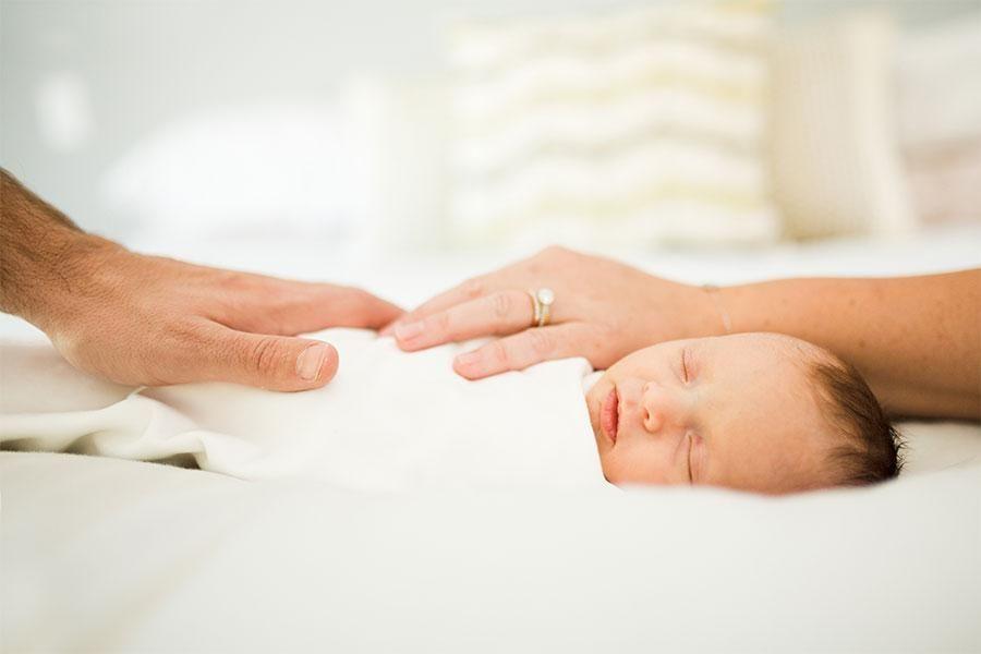 parents hold their hands on sleeping baby
