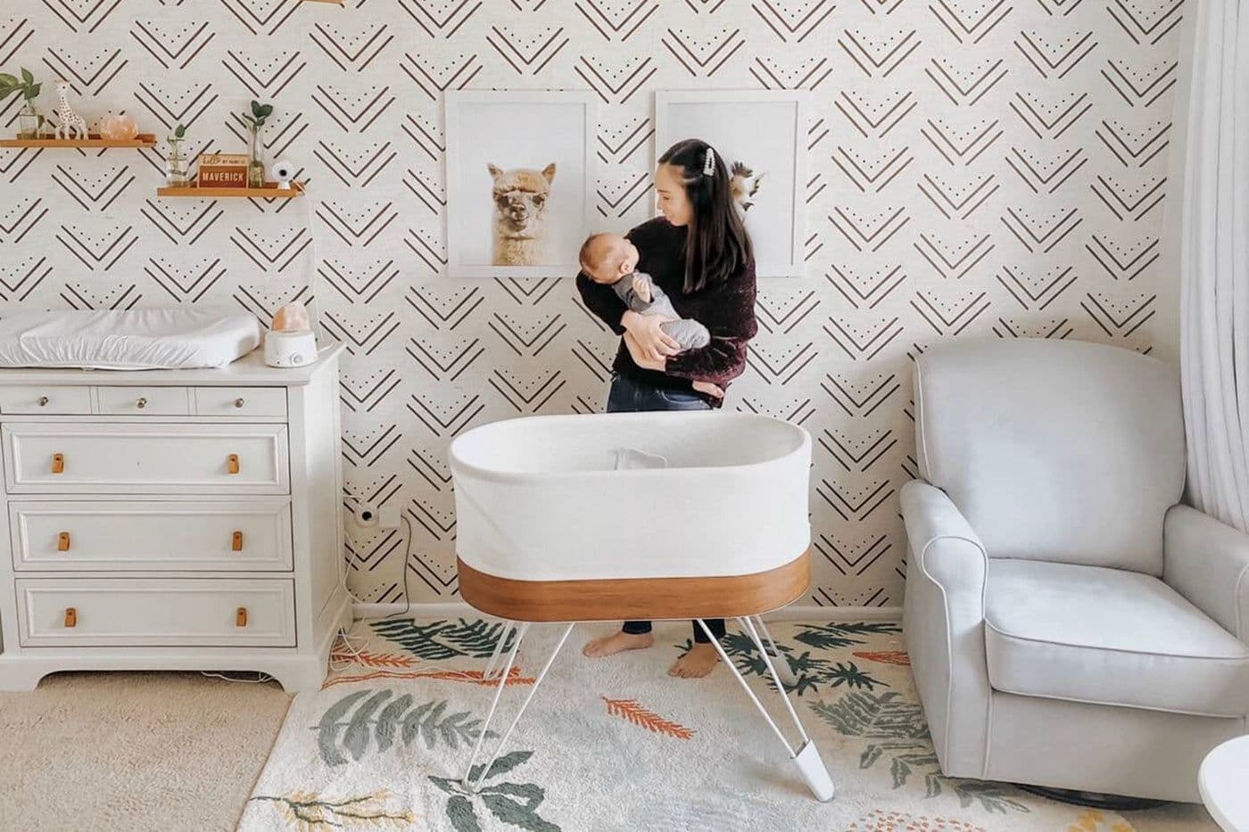Mom holds baby in nursery with patterned wallpaper